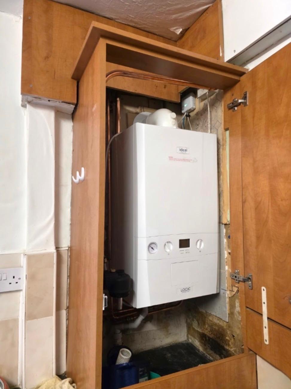 New Ideal Logic combi boiler installed inside a kitchen cupboard with neat copper pipework